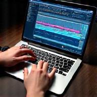 Hands manipulating audio editing software on a laptop